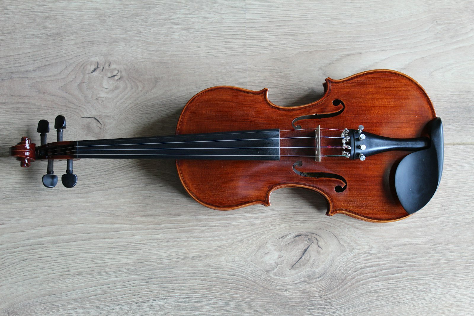 Violín apoyado sobre una tela clara, mostrando el clavijero y las cuerdas